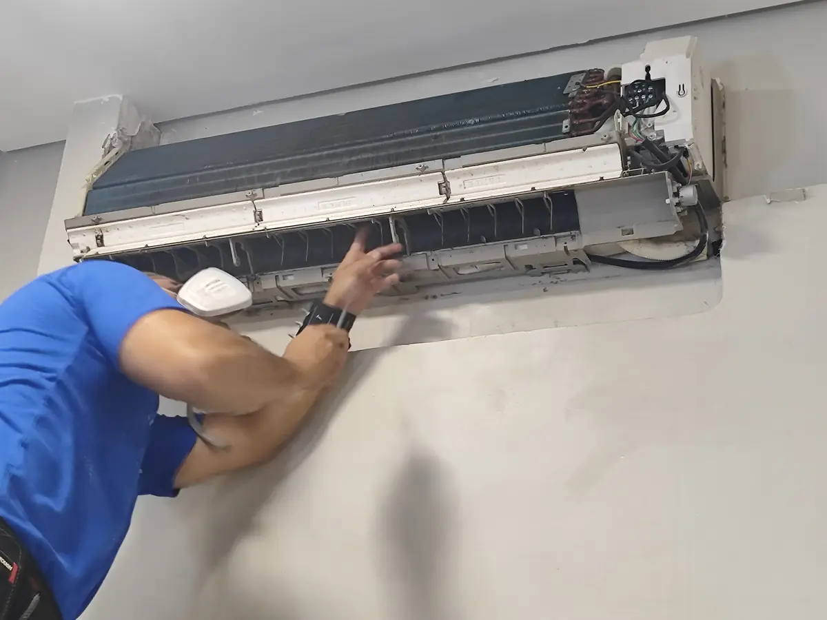 Técnico de máscara higienizando a serpentina de um ar-condicionado split